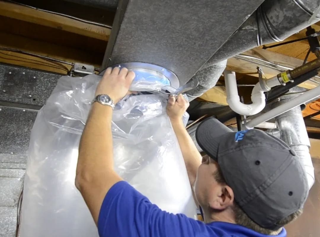 A man working on the ceiling of an air duct.