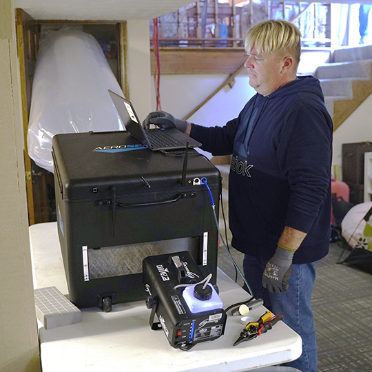 A man standing next to a printer on top of a table.