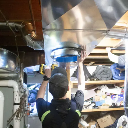 A man working on the inside of an air duct.