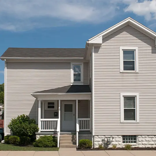 A white two story house with a porch and a blue sky.