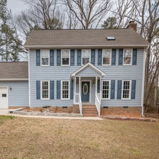 A blue house with white trim and steps leading to the front door.