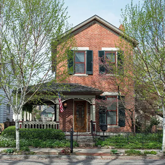 A brick house with trees in front of it.