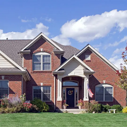 A large brick home with a green lawn in front of it.